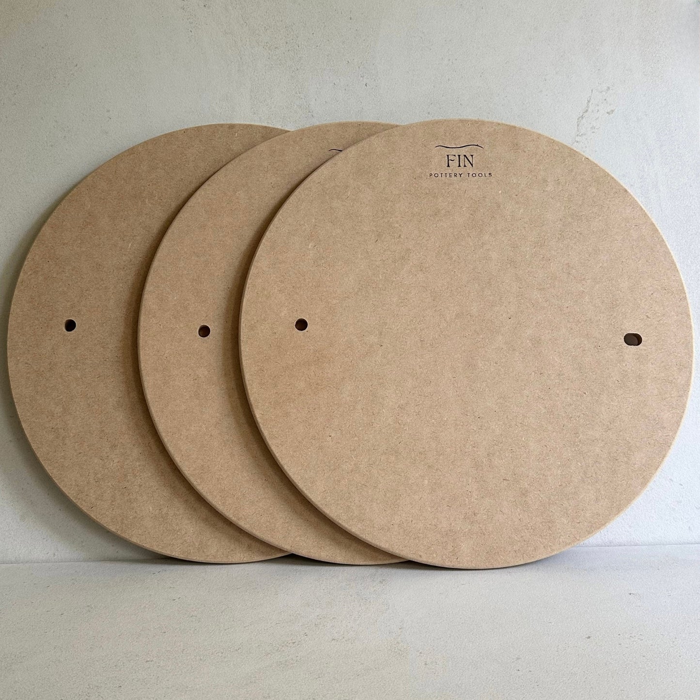 Three MDF pottery bats with pin holes. compatible with Venco or Shimpo wheels, placed on a flat surface.