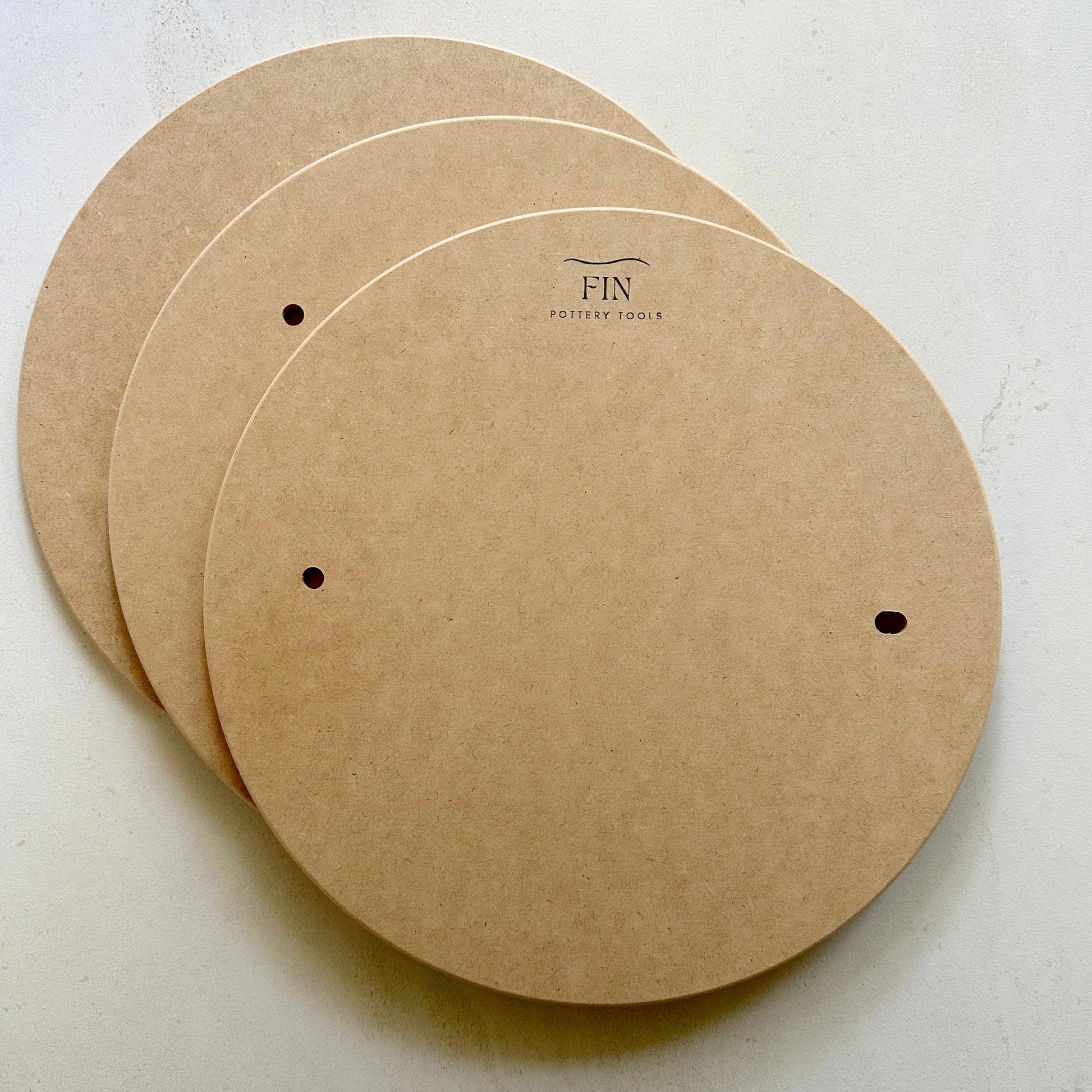 Three MDF pottery bats with pin holes. compatible with Venco or Shimpo wheels, placed on a flat surface.