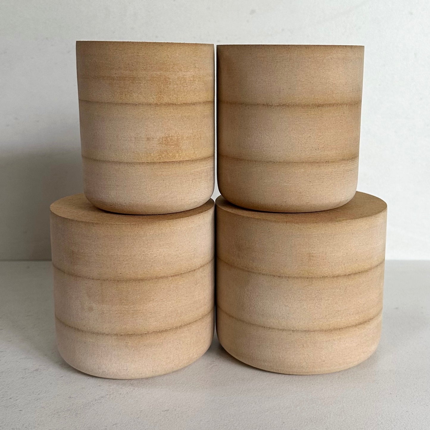 Four MDF mug moulds stacked on a light surface.