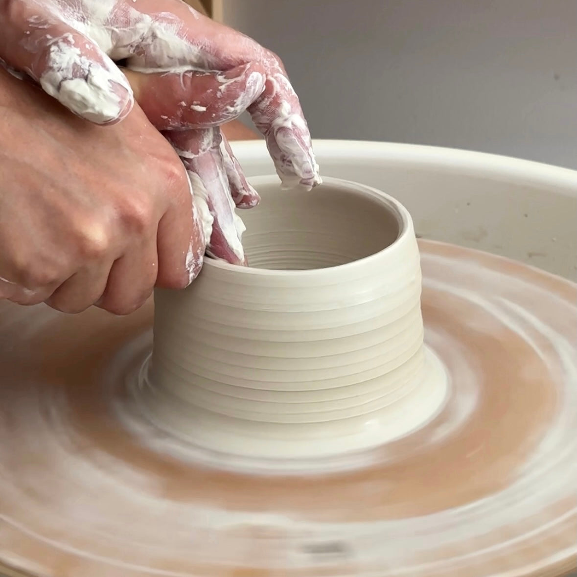 Close-up of potter throwing cylinder form on Fin Pottery Tools MDF pottery bat with pin holes.