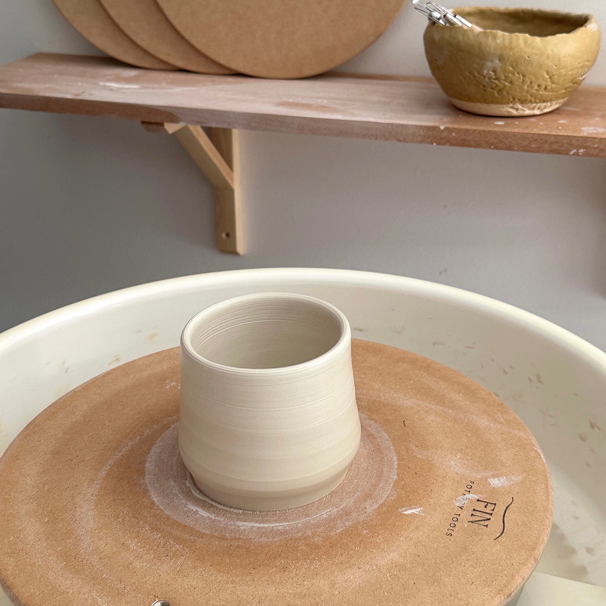 Close-up of clay mug on a Fin Pottery Tools MDF pottery bat with pin holes.